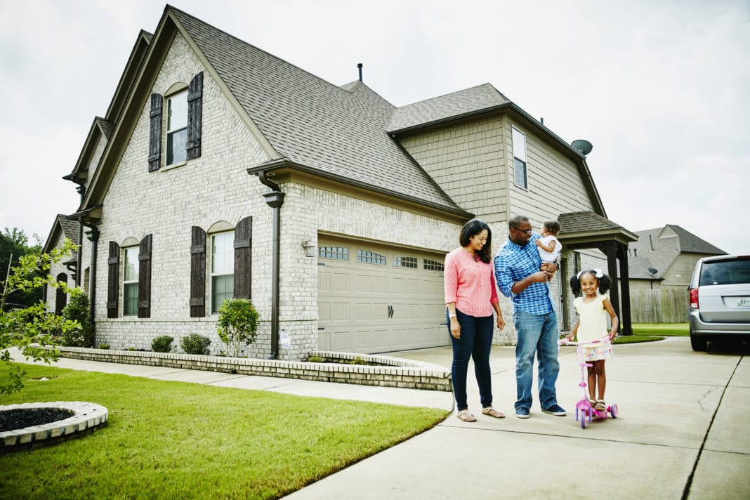 black family in driveway of new home