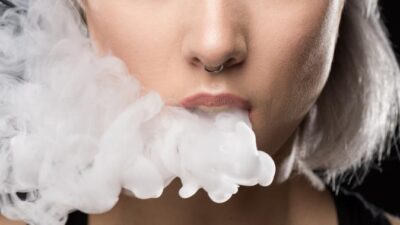 attractive-young-woman-vaping-and-blowing-smoke-on-black (1)