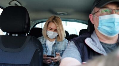 Uber - Coronavirus-woman passenger & male driver wearing facemasks (iStock)