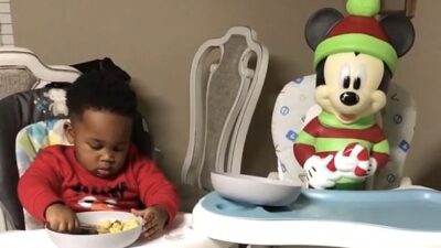 Toddler shares food with Mickey Mouse