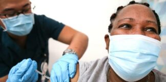 Black person (masked) getting vaccination / Getty