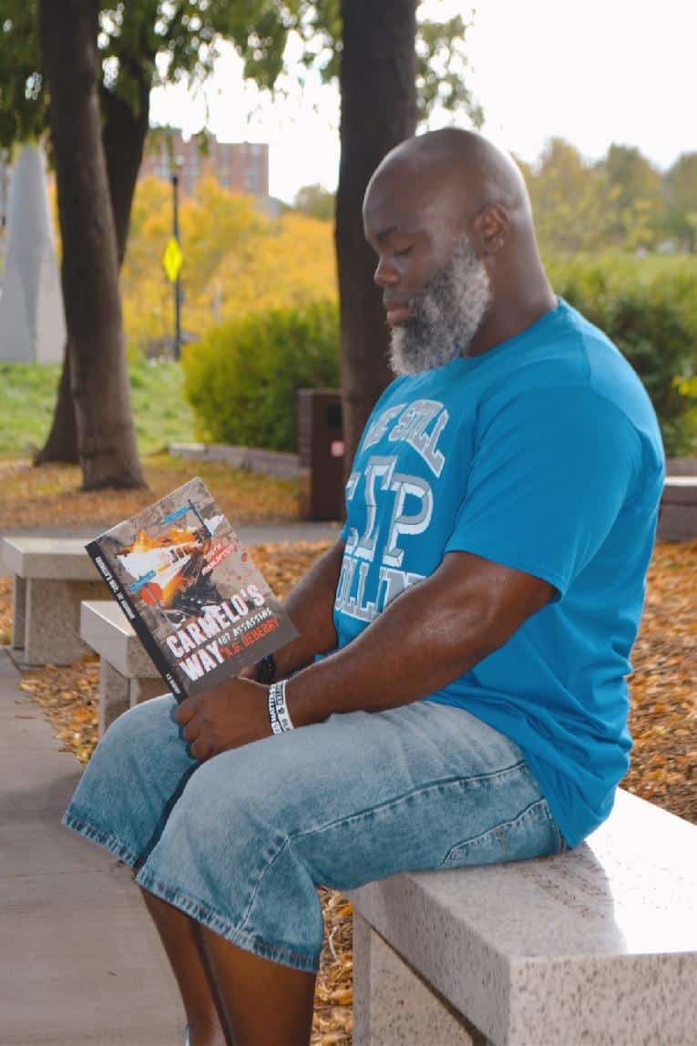 Armel Green (AG Deberry) reading Carmelo's Way in park setting