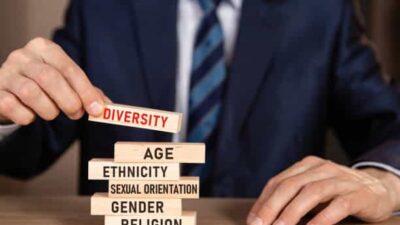 iversity concept. Business man building stack from wooden blocks.