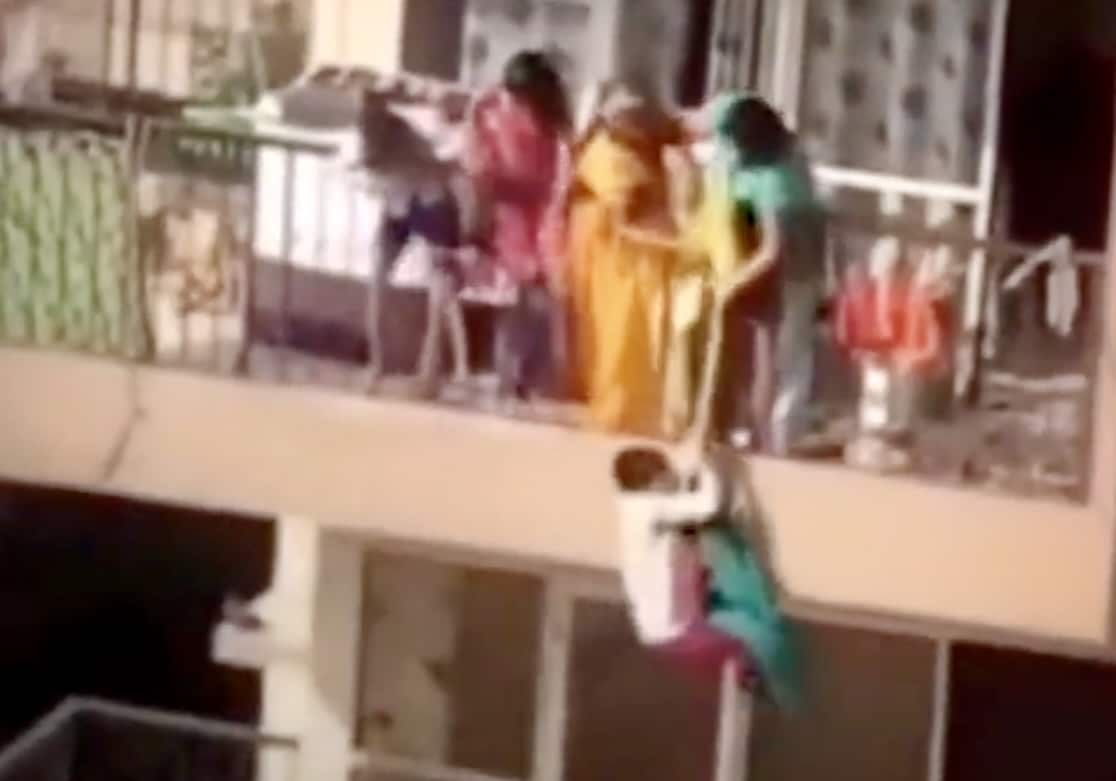 Woman dangles child over high rise balcony