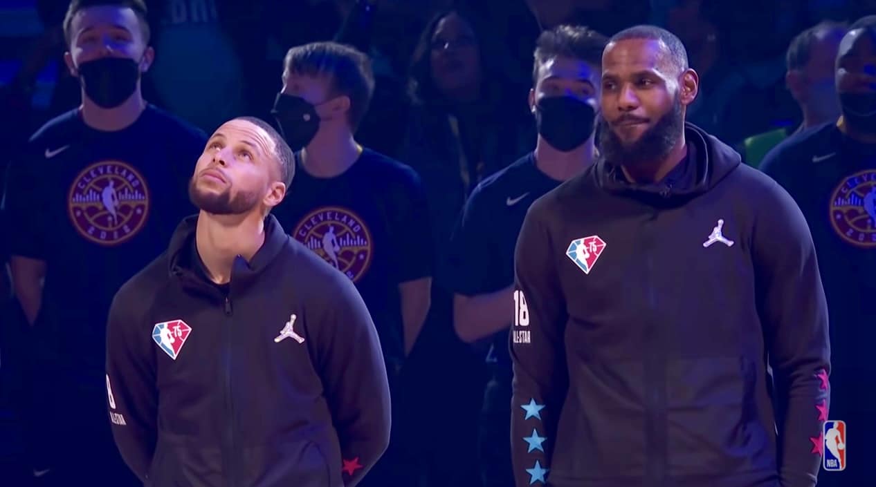 Steph Curry and LeBron James look on as Macy Gray sings the National Anthem at the 2022 NBA All-Star Game in Cleveland, Feb. 20, 2022