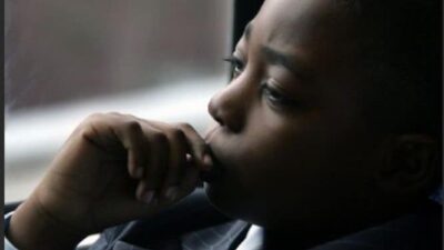 A Black child ponders while riding.