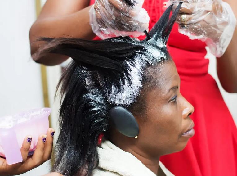 Black Woman getting hair relaxed with chemical