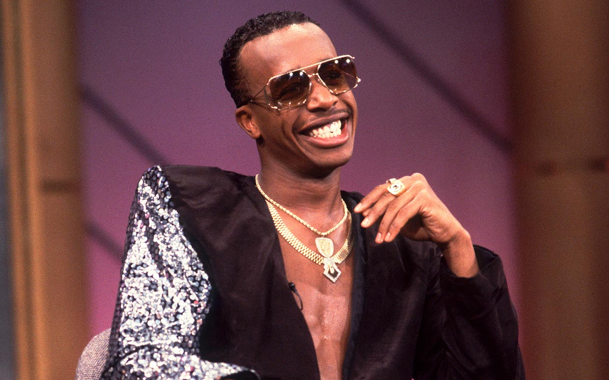 A seated MC Hammer smiles in 1990