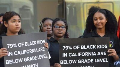 Black Students holding 'Below Grade Level' signs at California state capitol