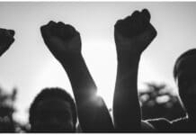 Black demonstrator people holding hands against racism - Focus on civil fists - Black and white edit stock photo