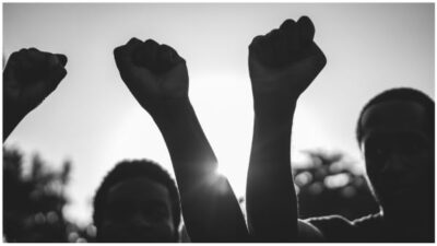Black demonstrator people holding hands against racism - Focus on civil fists - Black and white edit stock photo