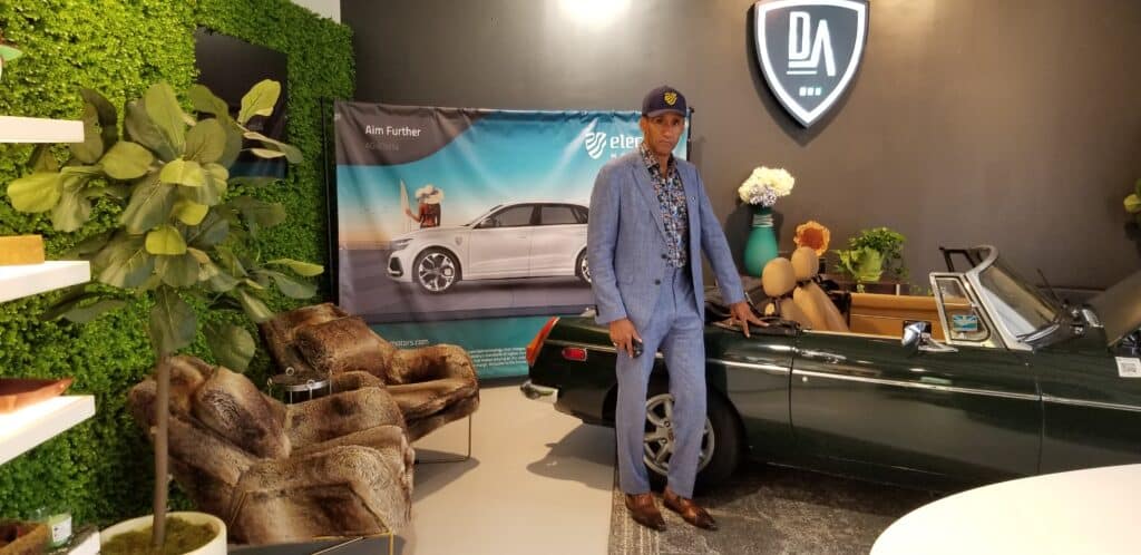 Derek Bailey, CEO of Derek Automotive, is in his showroom posing in front of a retrofitted manual transmission MG electric vehicle. (Photo Credit: JeffCars.com)