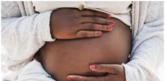 Close-up of a pregnant woman holding her belly - iStock