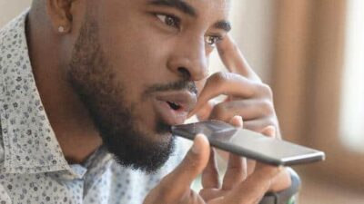 Man on iPhone talking to Siri - dreamstime