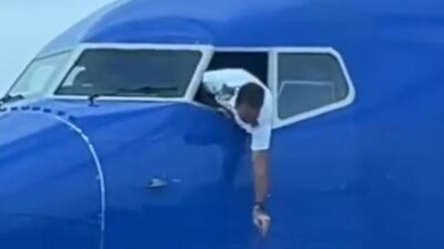 Southwest pilot hanging out of cockpit window to reteieve passenger's smartphone / via Southwest Airlines