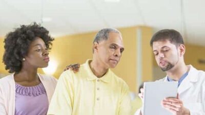 Patient (with wife) and doctor - Getty