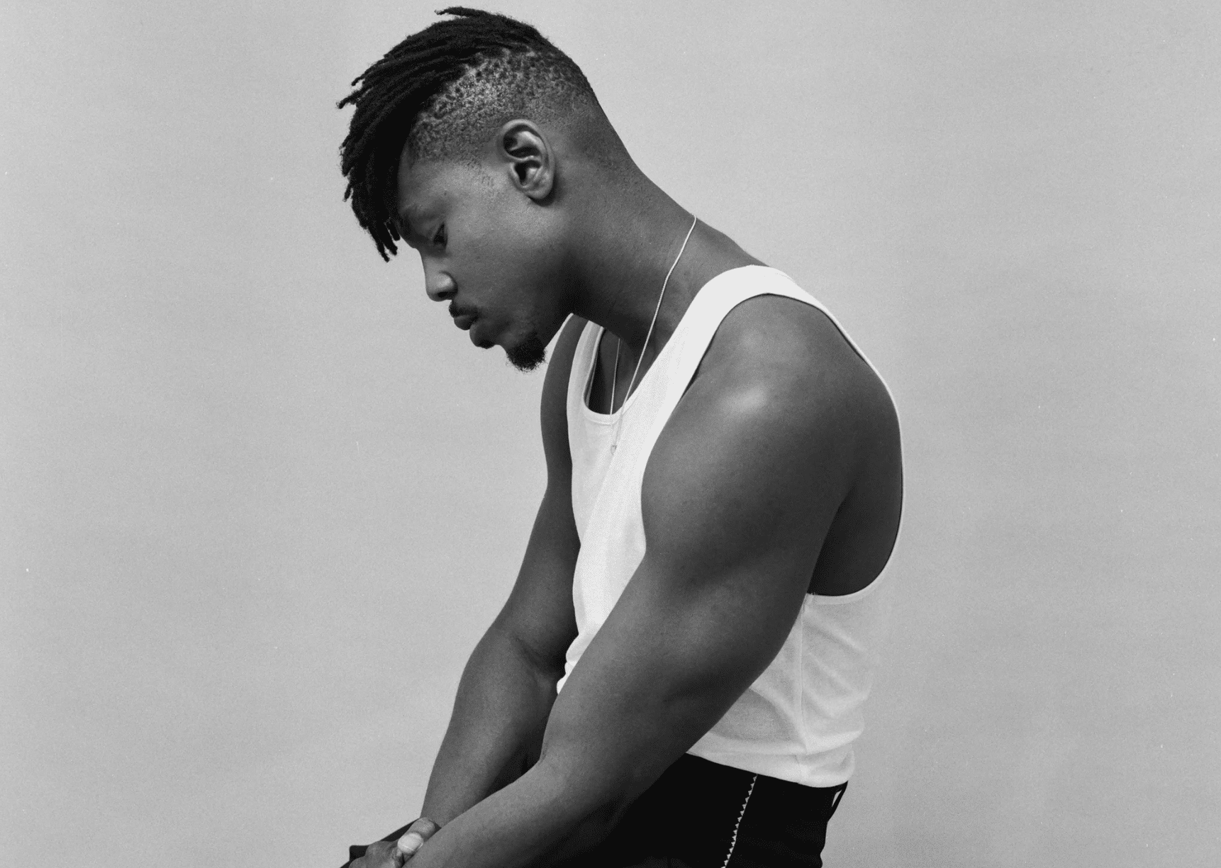 Ladipoe seated in white tank top
