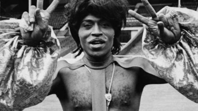 Singer Little Richard making peace sign and wearing an outlandish outfit as he prepares to perform at Wembley Stadium, 1972. (Photo by Rosemary Matthews/Keystone Features/Getty Images)