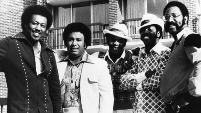 The Spinners pose in front of an apartment building in the 1970s