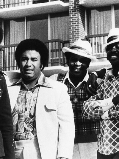 The Spinners pose in front of an apartment building in the 1970s