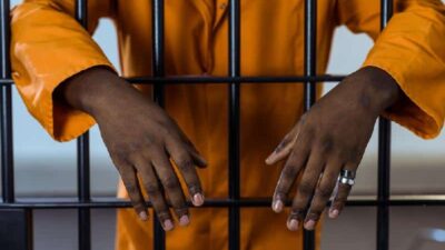 Man behind bars (in jail) - Depositphotos