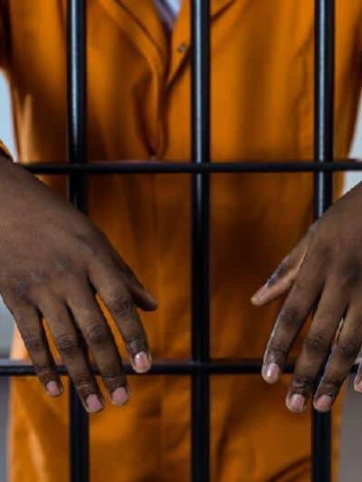 Man behind bars (in jail) - Depositphotos