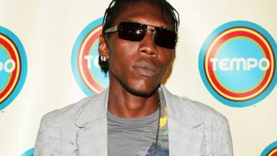 Vybz Kartel poses on a red carpet in sunglasses