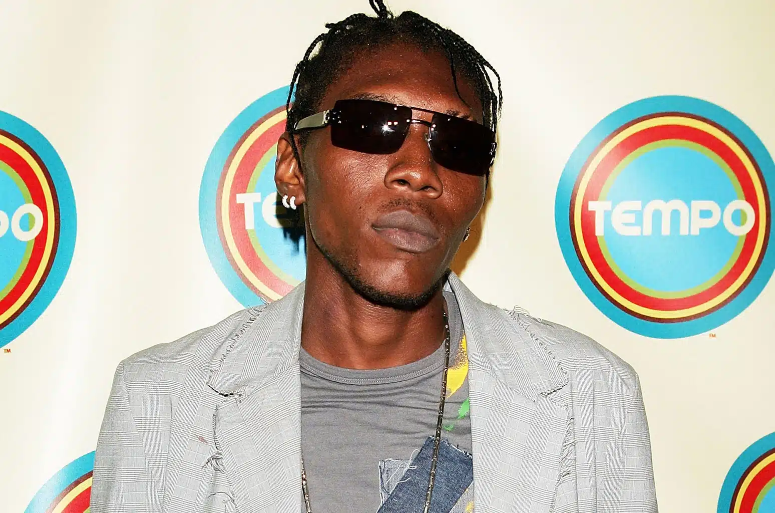 Vybz Kartel poses on a red carpet in sunglasses