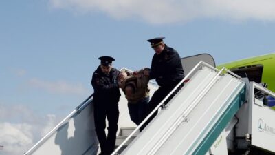 Drunk airline passenger being taken off plane - Depositphotos