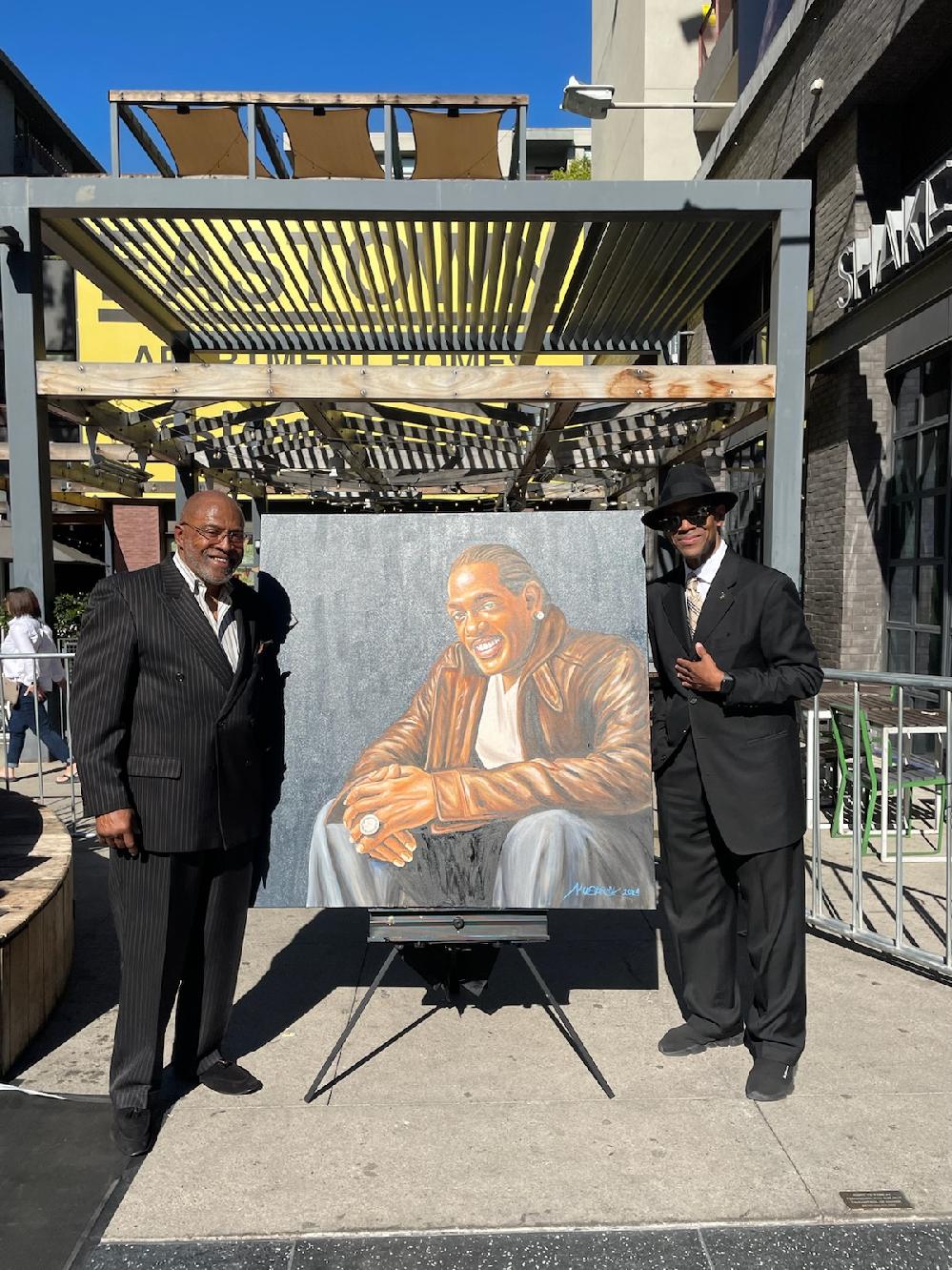 Artist and EURweb contributor Mohammad Mubarak (left) poses with Jimmy Jam Harris (right) at the Charlie Wilson star ceremony with his portrait of Wilson. 