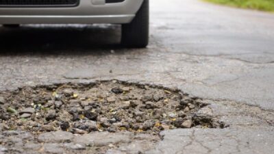 Pothole and car - Depositphotos