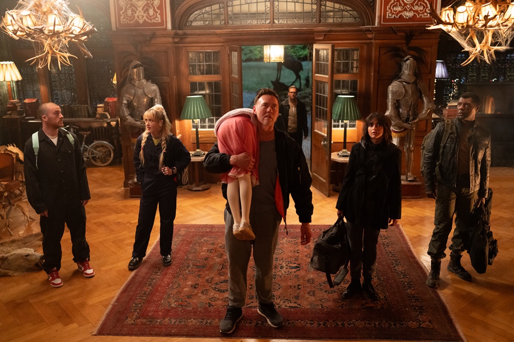 (from left) Dean (Angus Cloud), Sammy (Kathryn Newton), Abigail (Alisha Weir, back to camera), Peter (Kevin Durand), Frank (Dan Stevens, background), Joey (Melissa Barrera) and Rickles (Will Catlett) in Abigail, directed by Matt Bettinelli-Olpin & Tyler Gillett. &copy; 2024 Universal Studios