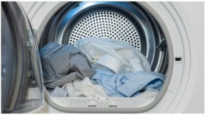 Close up view on clothes dryer with washed and dried shirts in and door open. stock photo