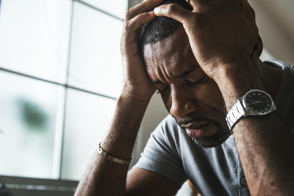 African man holding head with pain in hands