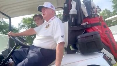 Donald Trump (and Baron Trump) in golf cart - via X screenshot