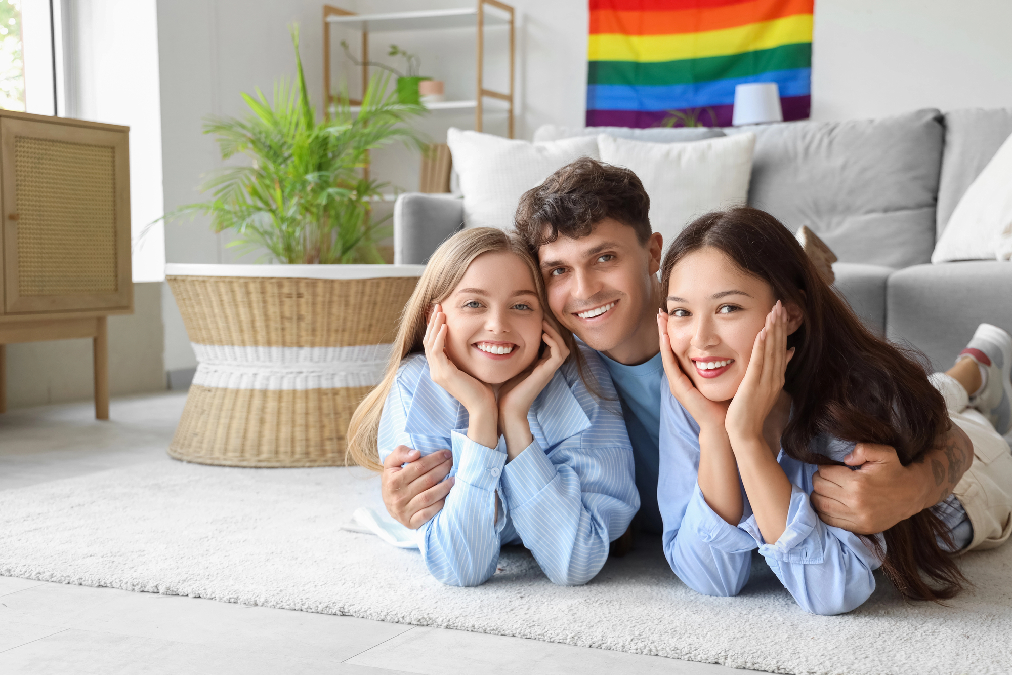 Young man with two women lying on floor at home. Polyamory