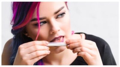 Panoramic shot of beautiful girl licking joint with weed