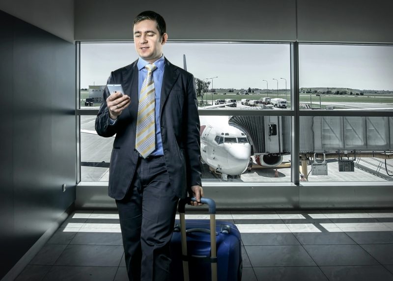 Traveler using mobile phone at airport - Depositphotos