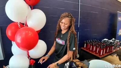 A young lady is seen setting up items at at the YOUNG3 event - screenshot
