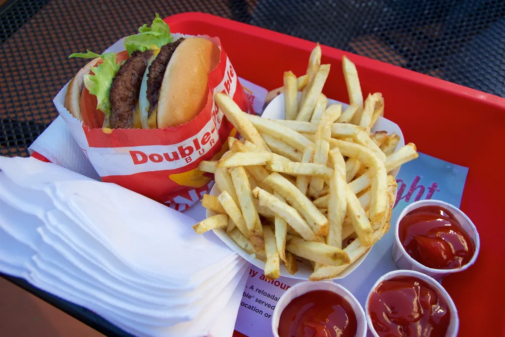 In n Out Double Double cheeseburger with animal style, burger with protein style, and french fries in a tray. — Photo by miles_around