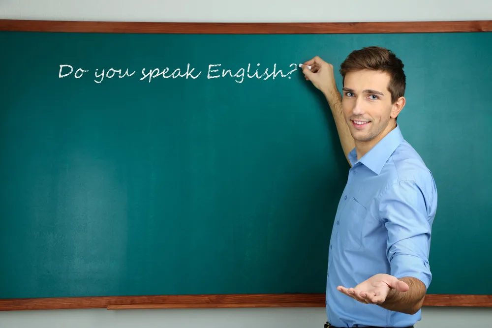 Young teacher near chalkboard in school classroom