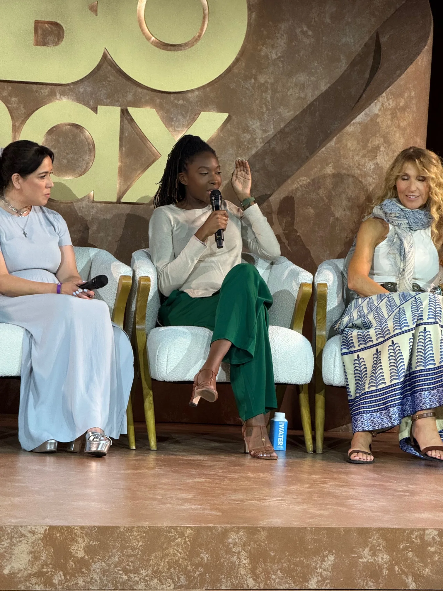Amber Jasmin Morrow, center, speaks into a microphone during a panel discussion, seated between two other women onstage at an HBO Max event.