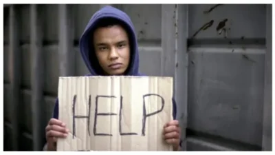 young boy holding Help sign
