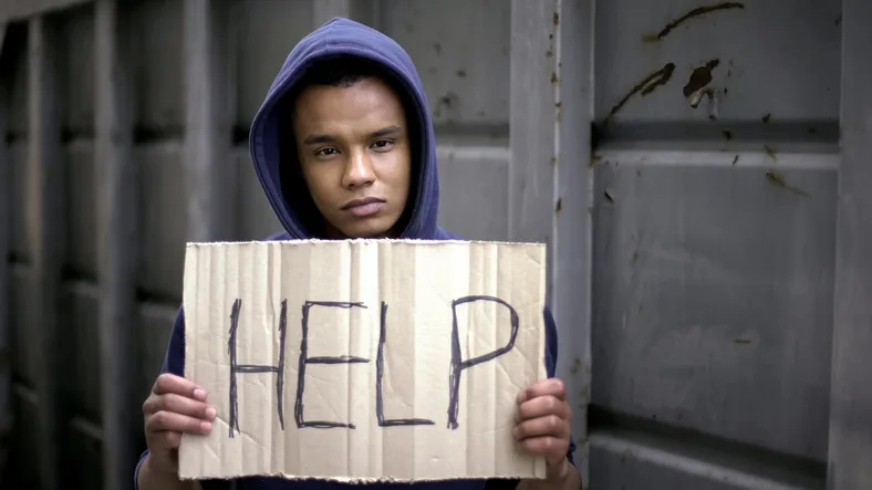 young boy holding Help sign