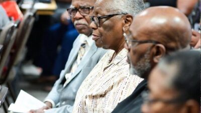 A community town hall scene showing elderly Black renters confronting representatives over rising rents / via GrokAI