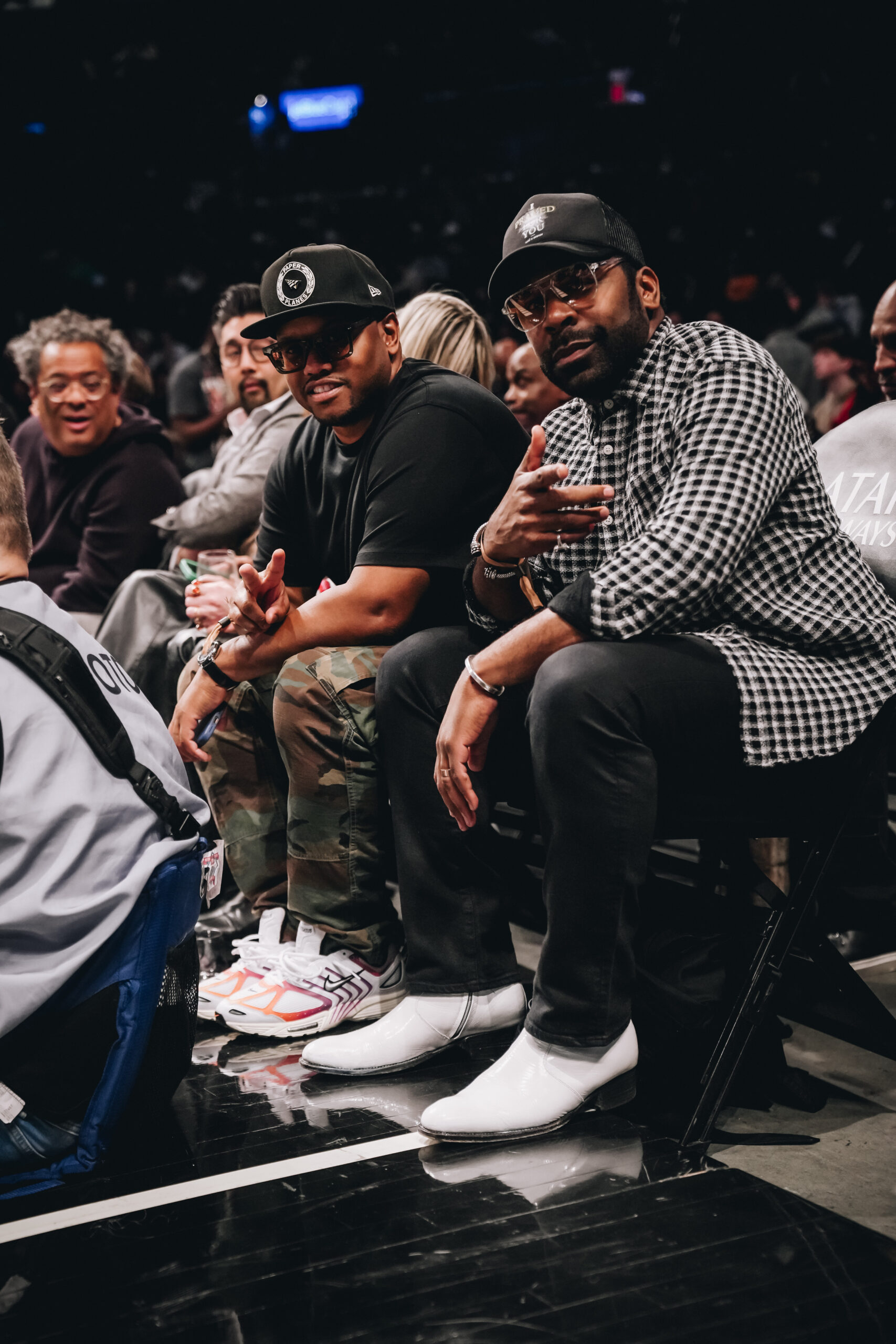 Calvin Spann sitting courtside at a basketball game with recording artist MAJOR.