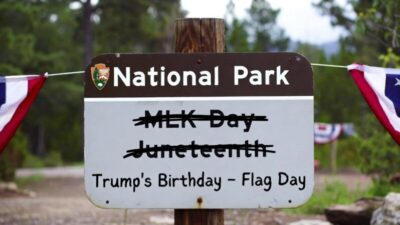 A satirical national park entrance sign where 'MLK Day' and 'Juneteenth' are crossed out and replaced with 'Trump&rsquo;s Birthday - Flag Day'