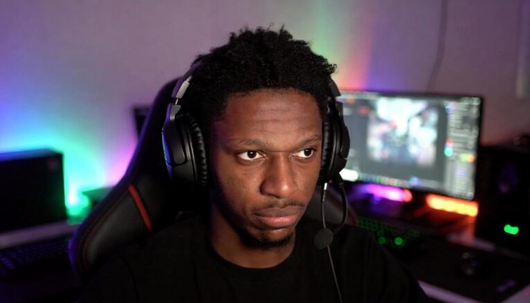 A young Black male Twitch streamer in a dimly lit room, wearing headphones, looking emotional and reflective - via GrokAI