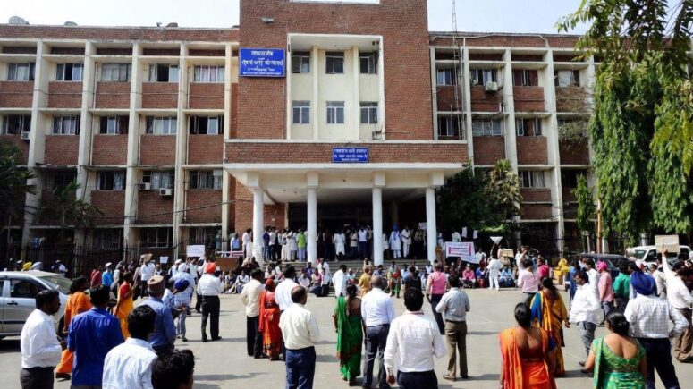 Exterior of a large public hospital in India with protesters gathered outside - via eurAI