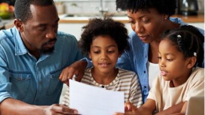 A middle-class AfricanAmerican family looking at health insurance documents at a kitchen table